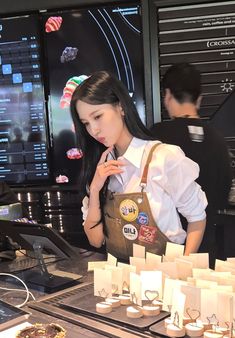 a woman standing in front of a counter with lots of small items on top of it