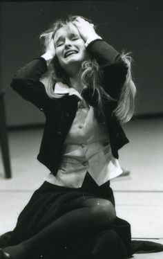 a black and white photo of a woman sitting on the ground with her hands in her hair