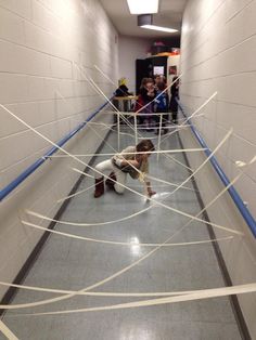 a boy is sitting on the floor in an empty hallway with tape wrapped around him