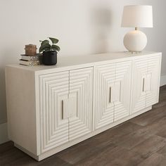 a white cabinet with two doors and a lamp on top of it next to a wall