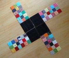 a cross made out of patchwork on top of a wooden floor