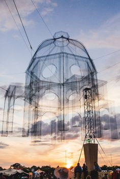 people are gathered around a large structure that looks like a face on top of the building