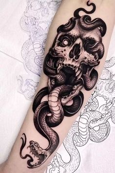 a black and white tattoo with a snake on it's arm, in the shape of a skull