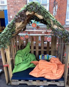 an outdoor play area made out of pallets and wood with green leaves on top