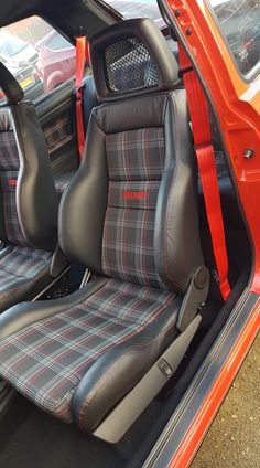 the interior of an orange car with plaid seats