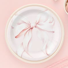 a white plate with a pink bow on it next to two spoons and utensils