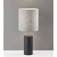 a black table lamp with a white shade on the top and a gold metal base