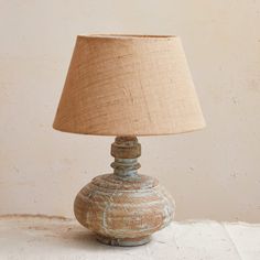 a table lamp sitting on top of a white surface next to a wall with a beige shade