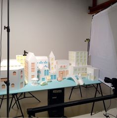 a table with model buildings on it and a camera set up to take the photo