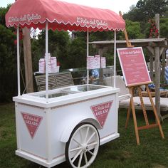 an ice cream cart sitting on top of a lush green field next to a sign