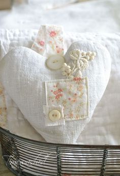 a heart shaped pillow sitting on top of a bed next to a basket filled with buttons