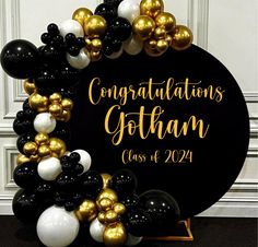 a black and gold balloon arch with congratulationss written on the front, surrounded by balloons