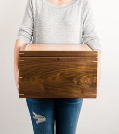 a person holding a wooden box with holes in it's sides and the lid