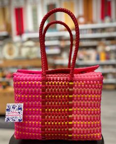 a pink and yellow woven bag sitting on top of a table