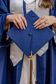 a woman wearing a blue graduation cap and gown holding a tassel in her hand