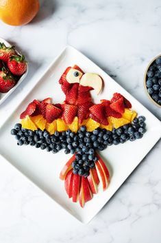 a white plate topped with fruit and an eagle cut out of it's wings