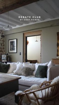 a living room filled with lots of furniture next to a stone wall and wooden beams