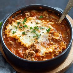 a bowl filled with pasta and sauce on top of a wooden cutting board