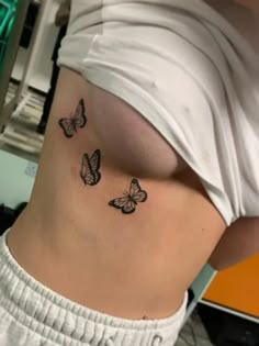 a woman's stomach with three butterflies on her left side ribcage tattoo