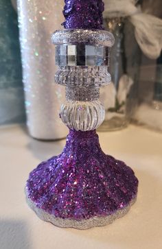 a purple glitter candle holder sitting on top of a table