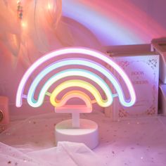 a colorful light sculpture sitting on top of a white table next to a pink wall