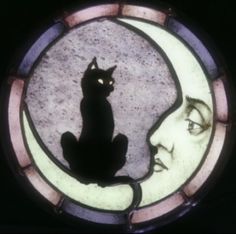 a stained glass window with a cat sitting on the moon