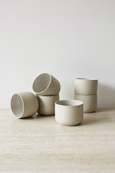 five white cups sitting on top of a table next to each other and one is empty