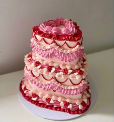 a three tiered cake with pink and red icing on it's side