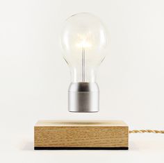 a light bulb sitting on top of a wooden block next to a roped cord