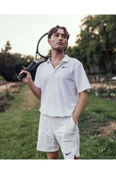 a young man holding a tennis racquet on top of a green grass covered field