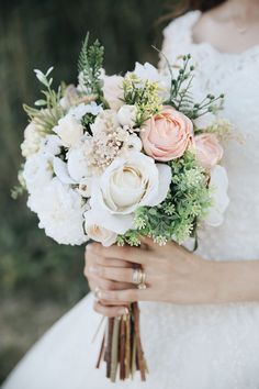 a bride holding a bouquet of flowers in her hands with greenery on the side