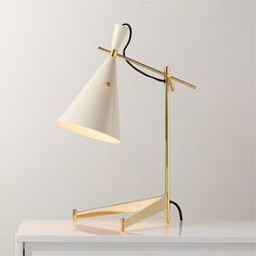 a white desk lamp on top of a table next to a black and gold object