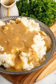 mashed potatoes and gravy in a bowl on a cutting board