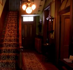 a hallway with stairs and lights in the middle of it is lit by two lamps on either side of the door