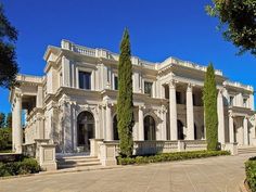 a large white building with columns and trees on the front lawn in front of it