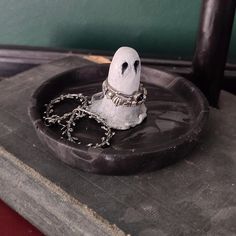 a small white bird sitting on top of a black plate with chains around it's neck