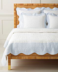 a bed with white linens and pillows on top of it, in front of a wall