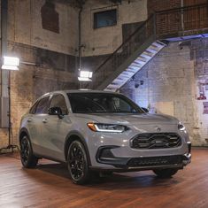 a silver suv is parked in an empty room with stairs leading up to the ceiling