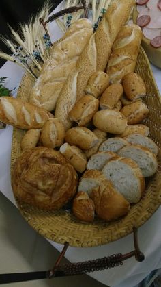 breads and pastries are arranged in a basket on a table with other food items