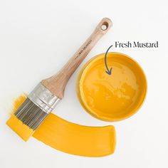 a paintbrush and yellow bowl with the words fresh mustard painted on it's side