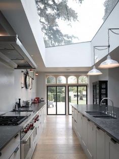 a kitchen with white cabinets and an open skylight above the stove top ovens