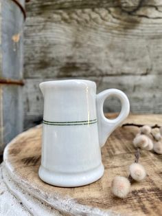 a white coffee mug sitting on top of a wooden table next to cotton floss