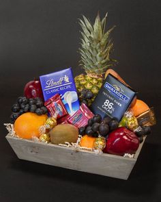 a fruit and chocolate gift basket with pineapple, blueberries, oranges, grapes, apples, bananas, milk