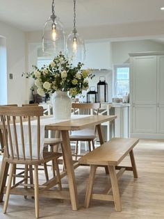 a dining room table and chairs with flowers in the vase