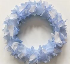 a blue and white wreath made out of tissue paper on top of a table next to a wall