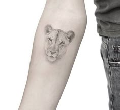 a small lion tattoo on the left forearm and right arm, next to a man's arm