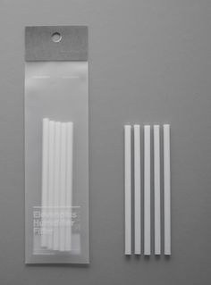 four white plastic straws in a package on a gray surface with the tag attached