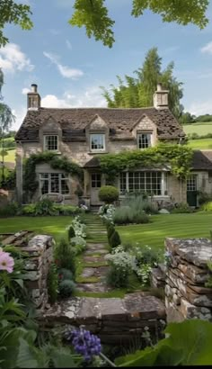 a stone house surrounded by greenery and flowers