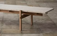 a white marble table sitting on top of a tile floor next to a wooden bench