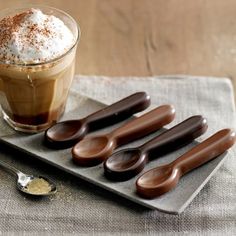 chocolate spoons on a tray next to a cup of coffee